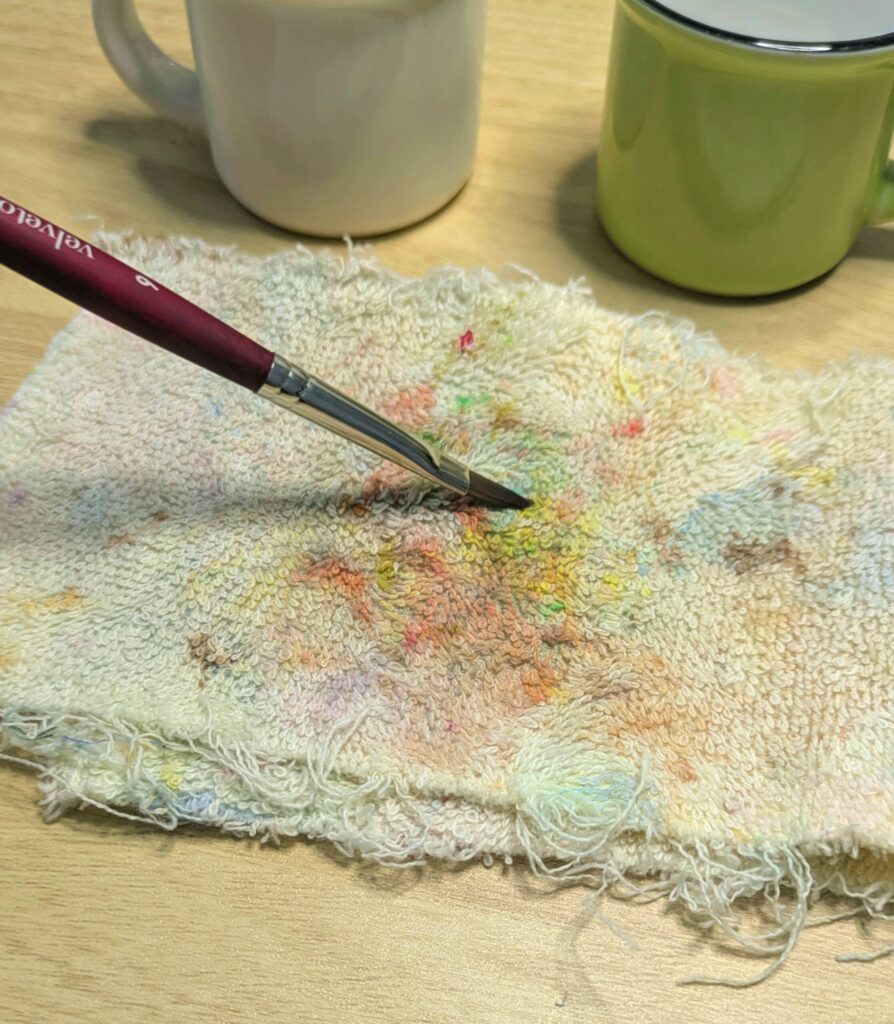 pretending to wipe clean a paintbrush on a piece of terrycloth